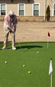 Carol Farrell resident of the Col. Robert L. Howard State Veterans Home try's out new putting green.