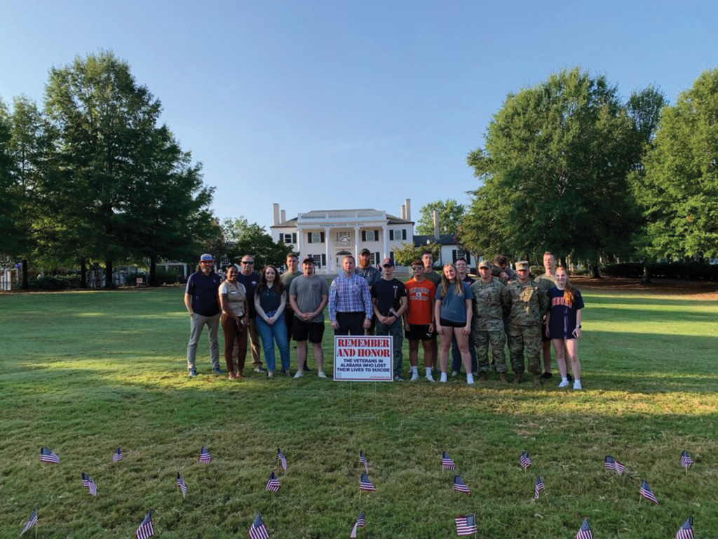 Photo of people standing behind remember and honor sign and flags in the ground